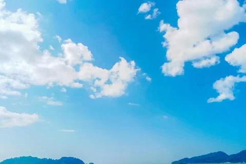 View of a small island with white clouds and a bright and beautiful blue sky Stock Photos