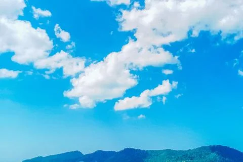 View of a small island with white clouds and a bright and beautiful blue sky Stock Photos