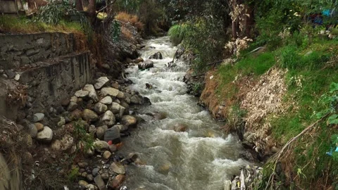 View of a small mighty river that crosses between two houses with stones and Stock-Footage 164566177