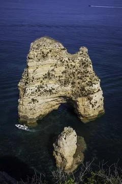 View of a small sailing boat navigating along the wild cliffs in the Algarve  Stock Photos
