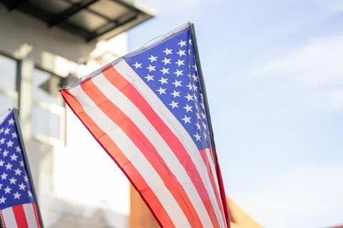 View of small waving American flags against a building and sky at a parade Stock Photos