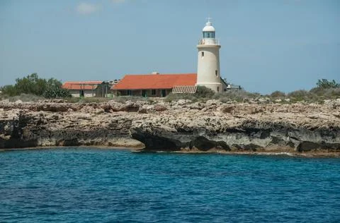 View of the small white lighthouse on the rock from sea . Landscape with Stock Photos