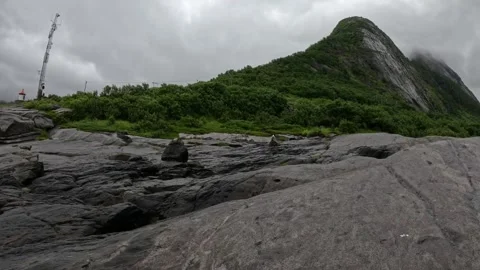 View of smooth granite coastline and green mountain ridge in Senja Norway 库存影片 342059428