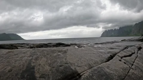 View of smooth granite rocks with Okshornan peaks across ocean in Senja Norway Stock-Footage 342059427