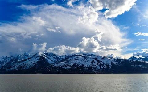 View of the snow-capped mountains in the clouds near the lake Gren Titon, USA Stock Photos