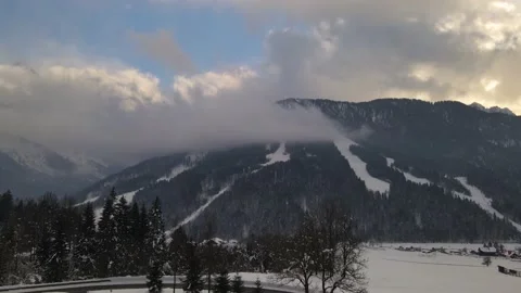 View of the snow-capped mountains covered with forest and clouds at sunset Stock-Footage 147545659