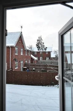 A view of snow-covered backyard and red brick houses through an open window. Stock Photos