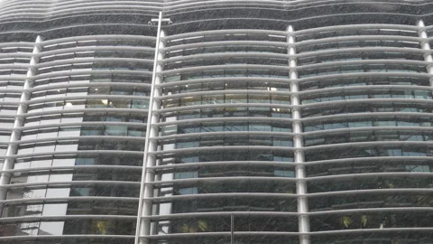 A view of snow falling in front of a glass building. Stock Footage 116687836
