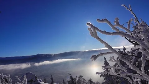 View of snowy mountains with clouds floating. sun comes out from behind snow- Stock Footage 317610829