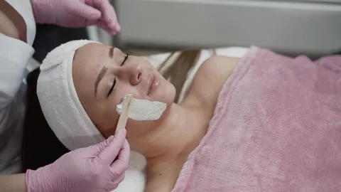 View of spa procedure of applying mask with spatula on female face in salon Vídeo Stock 149792104