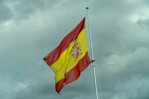 View of Spanish Flag in the Wind with Dark Storm Clouds in the Background Stock Photos