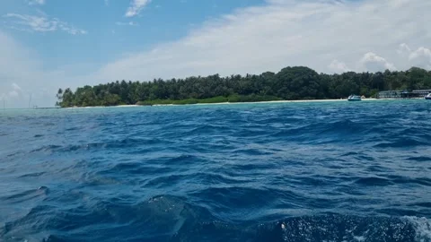 View from a speeding boat approaching a tiny Maldivian island, with dense green 動画素材 323246197