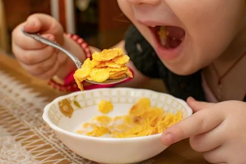 View of a spoon with corn flakes in the hand of a little girl Stock Photos