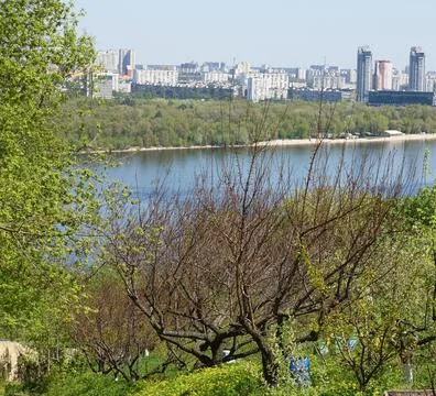 View of spring trees against the background of the Dnieper and Kiev buildings Stock Photos
