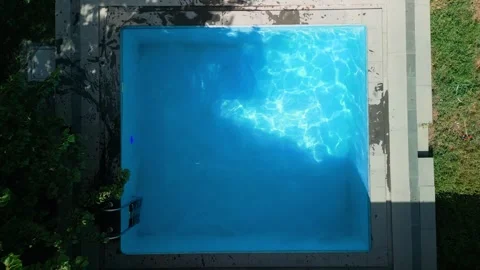 View of a square-shaped swimming pool on a bright sunny day Stock Footage 251011447