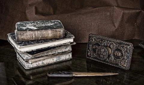 A view at a stack of ancient stained books by a metallic artifact and an old  写真素材