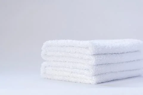 View of a stack of white folded terry towels on a light background. Stock Photos