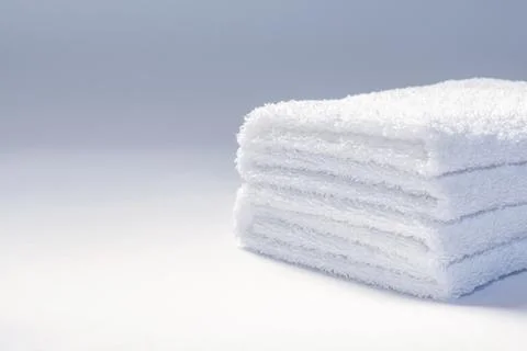 View of a stack of white folded terry towels on a light background. Stock Photos