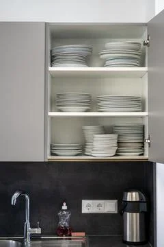 View of stacks of plates in a white open wall cabinet in the kitchen Stock Photos