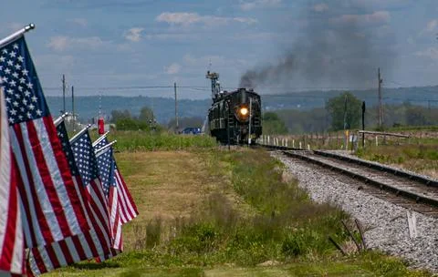 View of a Steam Engine Approaching, Blowing Smoke and Row American Flags Blowing Stock Photos