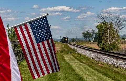 View of a Steam Engine Approaching, Blowing Smoke and Row American Flags Blowing Stock Photos