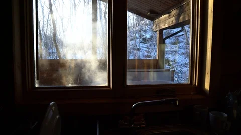 View of steaming hot tub through cabin window on a snowy day, 4k, UHD Stock Footage 86469371