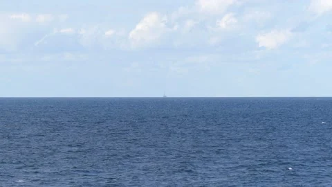 View from steep coast to horizon of the ocean - blue sky - a ship far away Stock Footage 139227181