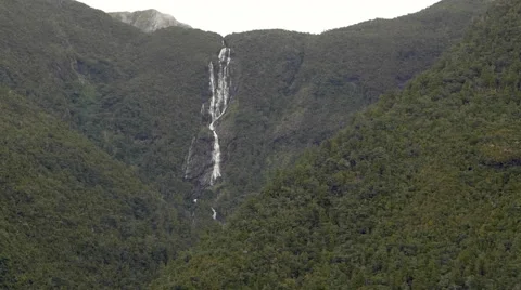 View of Stirling Falls flowing through mountains at Milford Sound, South Island, Stock Footage 51471389