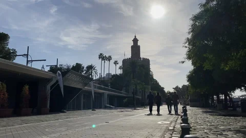 A View from a stone arch onto Sevilla riverside promenade with cyclists and 스톡 동영상 327555185