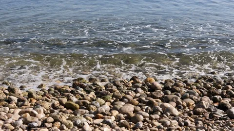 View of a stone beach with a clean transparent water and relaxing waves Stock Footage 125561942