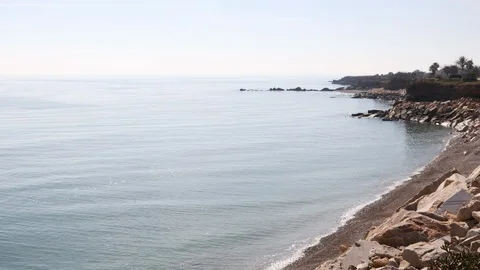 View of a stone beach with a clean transparent water and relaxing waves Stock Footage 125561944