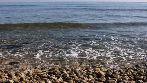 View of a stone beach with a clean transparent water and relaxing waves Stock Footage 125562569