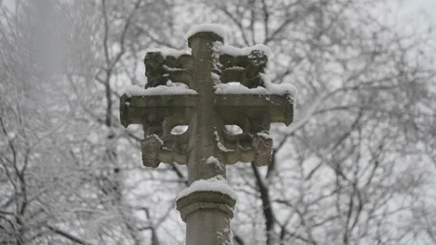 A view of a stone cross during snowfall. Stock Footage 228671501