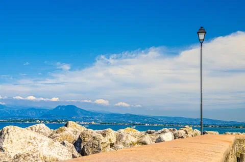View from stone pier mole of Garda Lake water with Monte Baldo mountain range Stock Photos