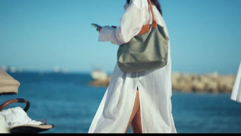 View of a stroller near the shoreline while a woman in a flowing white cover up Stock Footage 339773714
