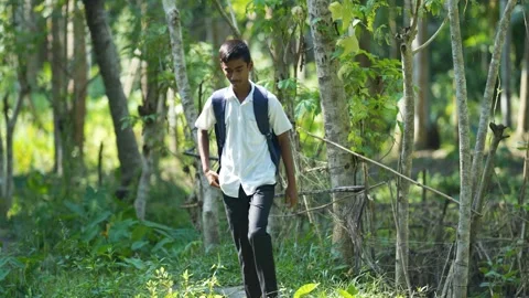 View of a student walking through a lush forest in Bogura, Bangladesh. 스톡 동영상 334957367