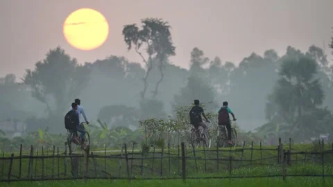 View of students cycling on a rural path during sunset, Bangladesh. 스톡 동영상 335553111
