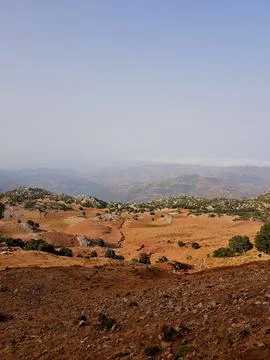View from the summit: below, sunlit valleys, rolling hills, and slopes extend Stock Photos