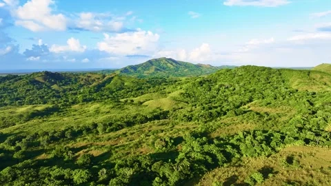 A view of a sun-drenched mountain range. Wooded foothills under a cloudy sky. Stock Footage 329010742
