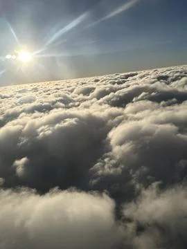 View of the sun over fluffy clouds from an airplane. Stock Photos