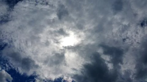 View on the sun through white clouds on the blue sky background Stock Photos