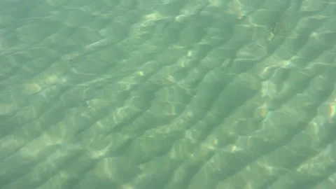 View of a sunlit sandy bottom through clear blue water Stock Footage 252018658