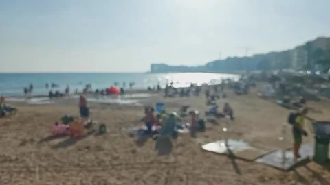 View of a sunny beach in out of focus. People are sunbathing and swimming i.. Stock-Footage 242486612