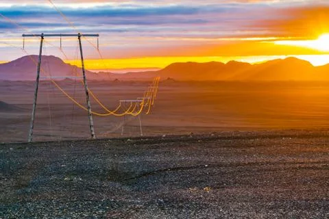 View of sunset with the high voltage cables Stock Photos