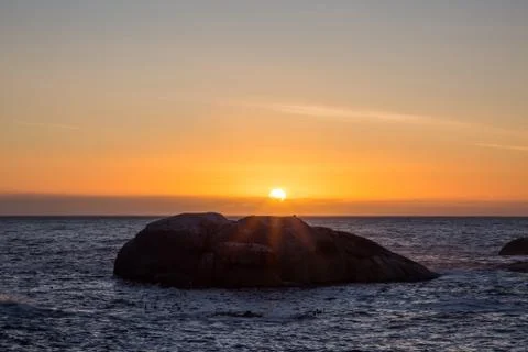 View of sunset over ocean with big rock Foto stock