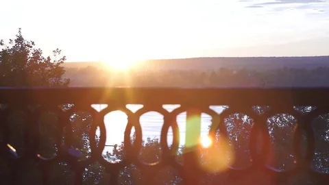 View of the sunset. The sun sets over the river and shines through the railin Stock Footage 76834260