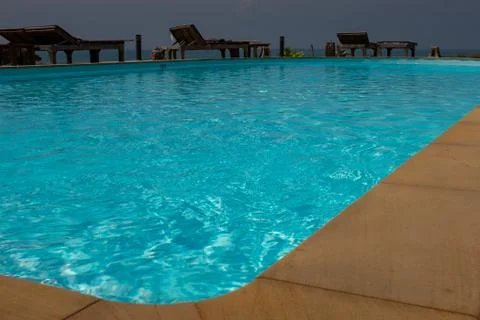 The view of swimming pool from the corner of the pool with sun lounges in the Stock Photos