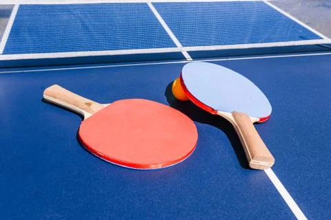 View of the table for playing table tennis. Two rackets and an orange ball. S Stock Photos