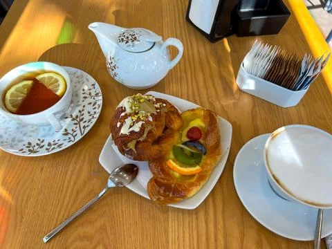 View of the table set for breakfast with hot drinks and sweet pastries Stock Photos