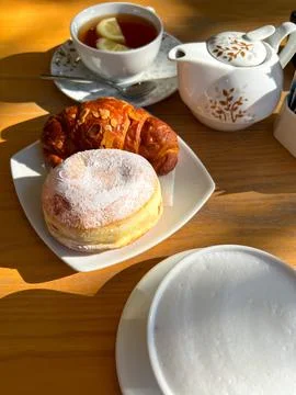 View of the table set for breakfast with tea and sweet pastries in the sun Stock Photos